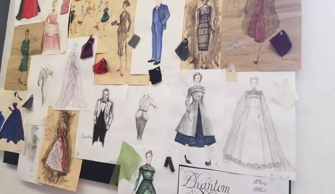 A board of outfit sketches and fabric swatches pinned up on a wall.
