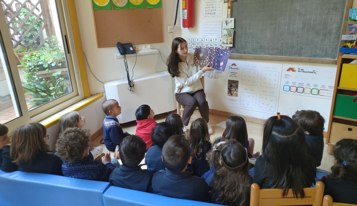 A student in her teaching internship reads a picture book to a group of school children.