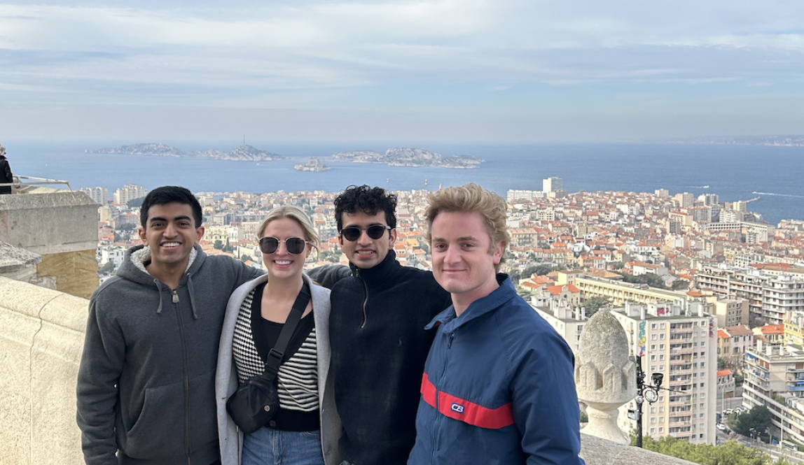 Four students at viewpoint in Nice, France - posing with city and ocean behind them 