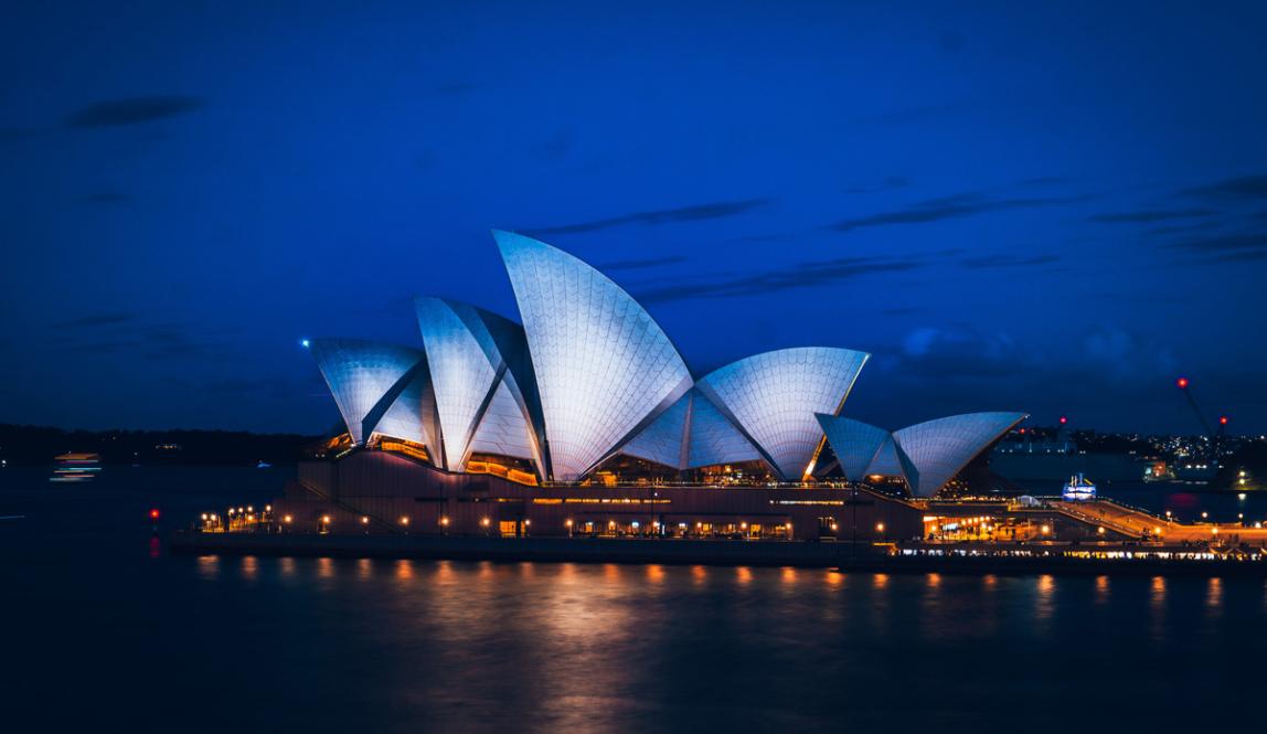 a lit up Sydney Opera House at night over Sydney Harbour