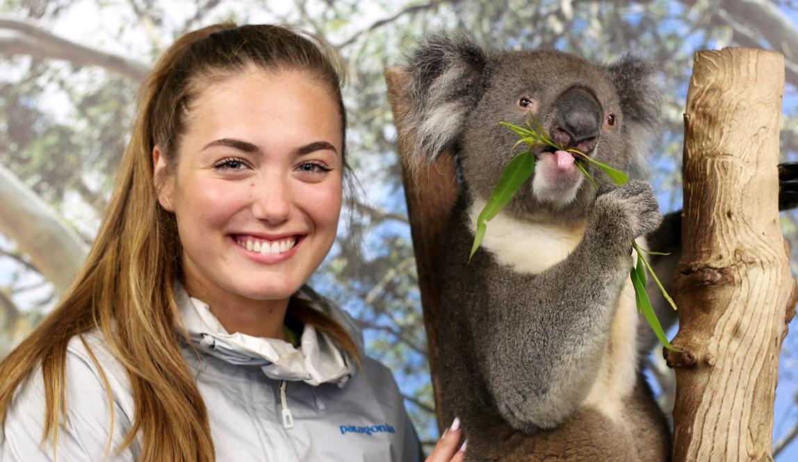 a student poses smiling next to a koala