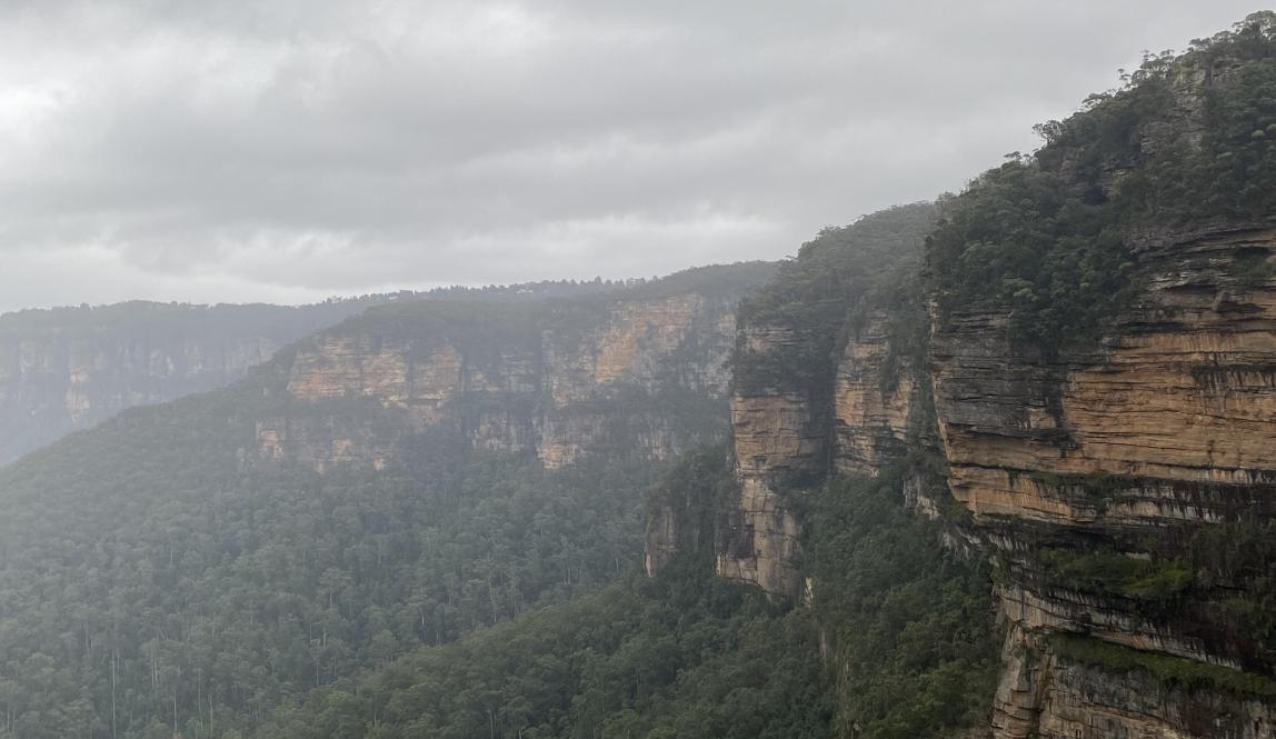 Another wide view of the Blue Mountains but with rocks peaking through the right-hand corner. 