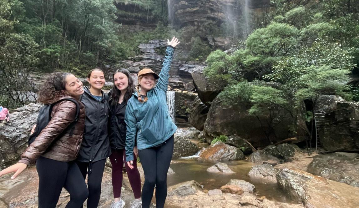 A group of friends posing in front of a waterfall at the Blue Mountains. 