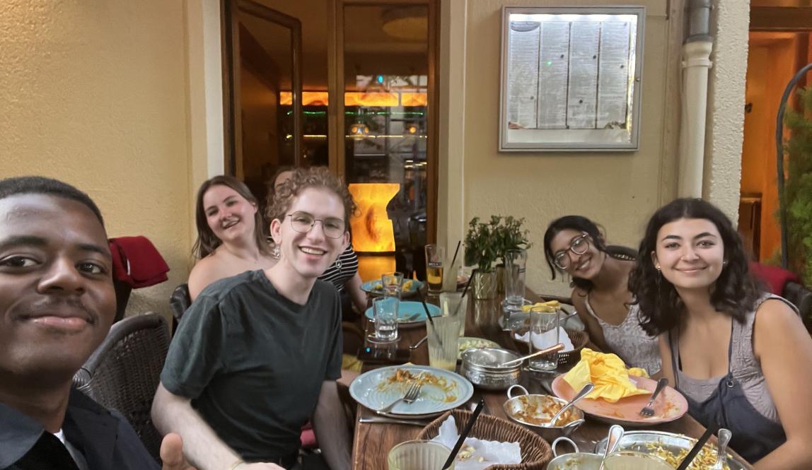 Selfie of six students sitting at a full table in a restaurant.