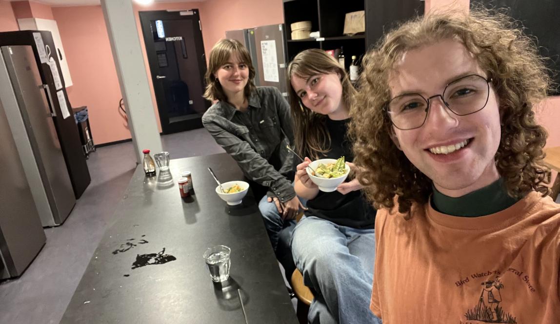 Selfie of three students sitting at a counter with bowls of curry. 