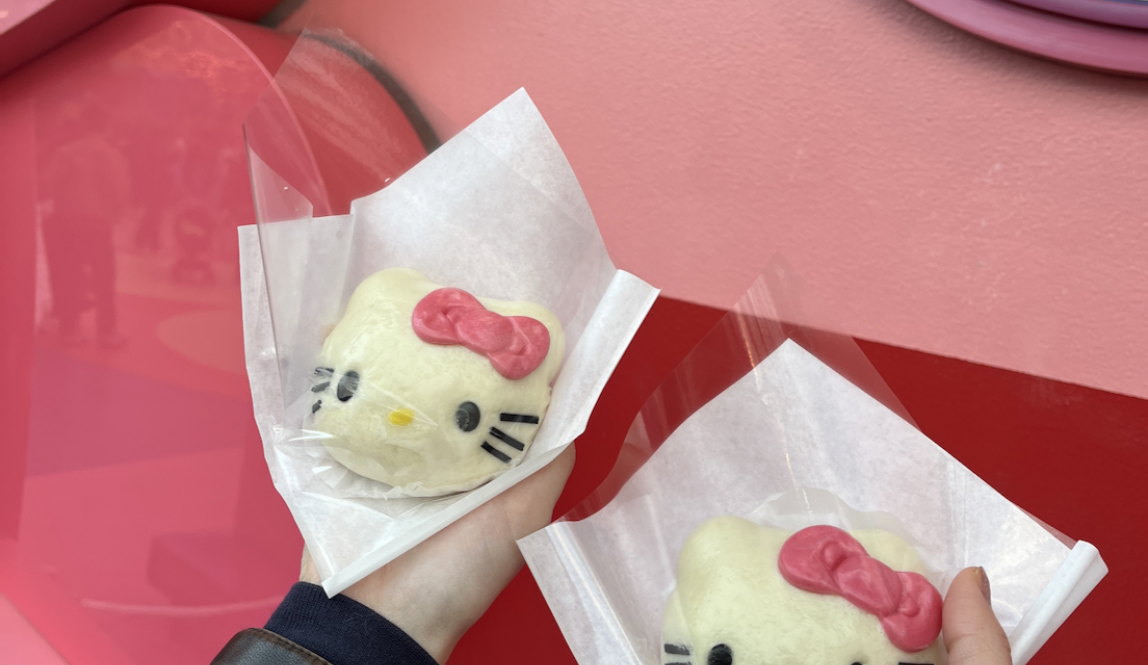 Two Hello Kitty cheese and meat buns in front of a pink bakery