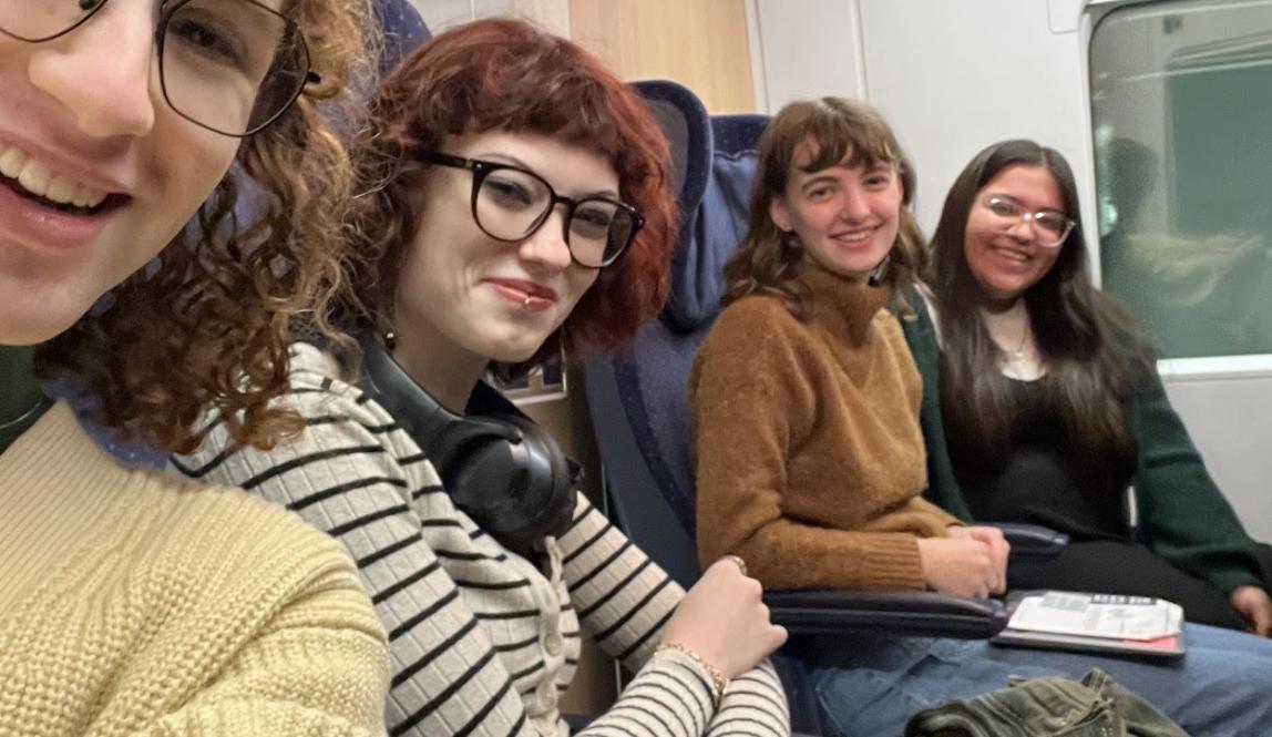 Four students sit in a row on a train. 