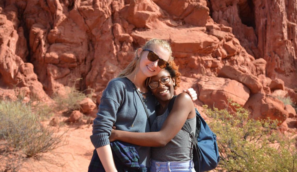 two students embrace for a photo