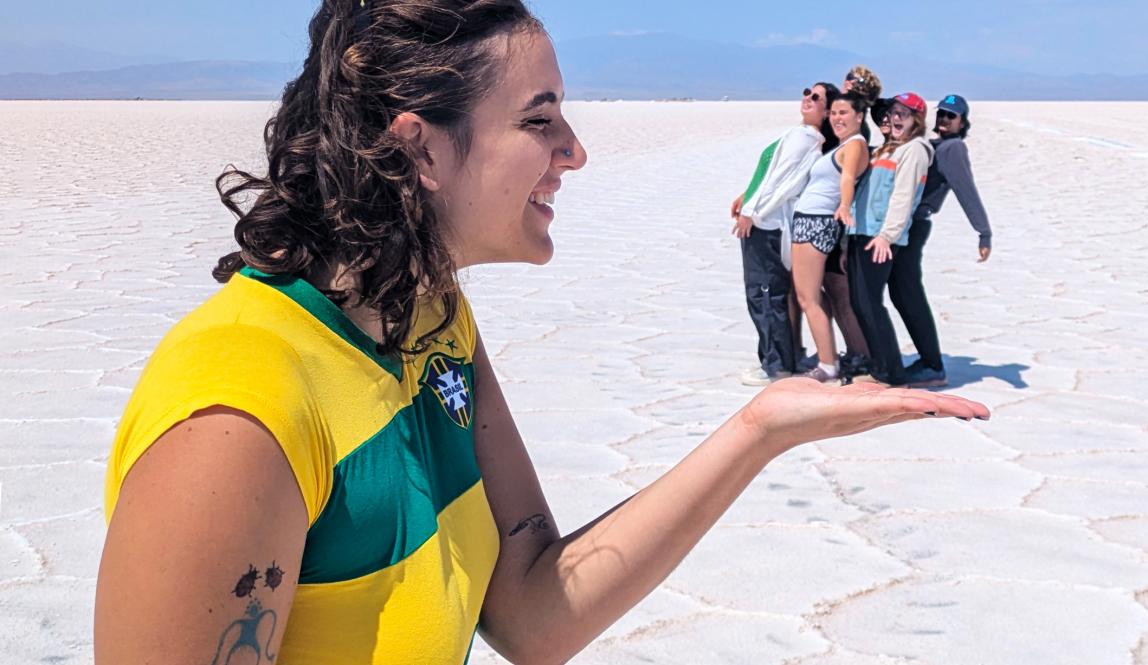 one student is in the foreground of the photo holding out their hand, while a group of students in the distance appear to be in her hand in Salta