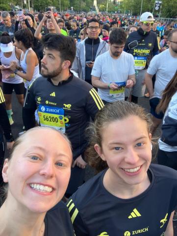 Two girls smile for a selfie in a crowd of runners before the start line of a race.
