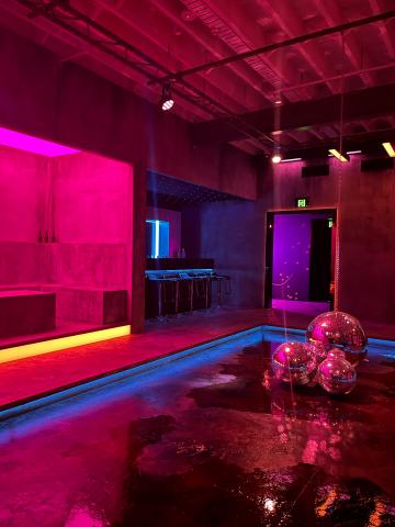  A room showcasing an empty bar and disco balls on the ground. Red and yellow lights light the room.