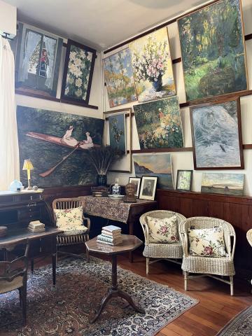 shows the inside of a room modeled to look like a painting workshop; there are some chairs, a mini table and various paintings by Claude Monet hung on the wall
