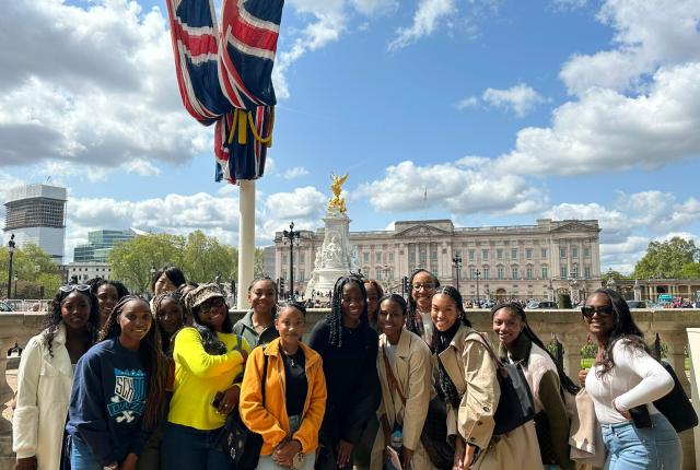 group of london students standing next to british flag in front of buckingham palace