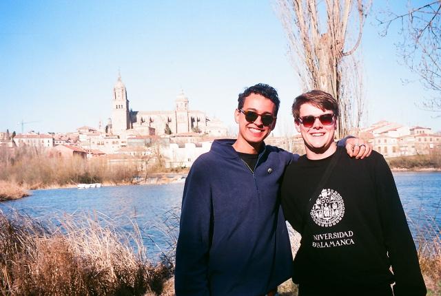 Two students standing in front of water with the cathedral in the background.