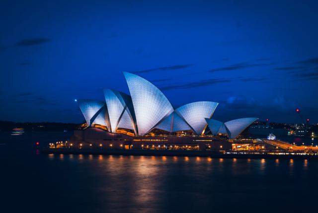 a lit up Sydney Opera House at night over Sydney Harbour