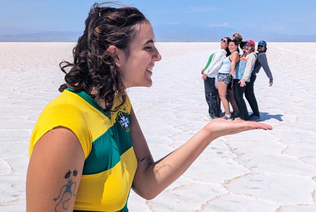 one student is in the foreground of the photo holding out their hand, while a group of students in the distance appear to be in her hand in Salta