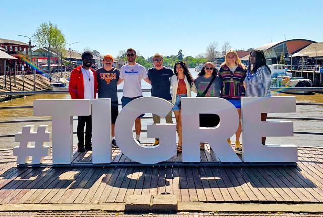 a group of students pose for a photo with a sign that says "#TIGRE"