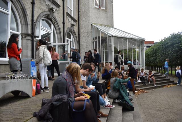 students sitting on steps in front of stone building