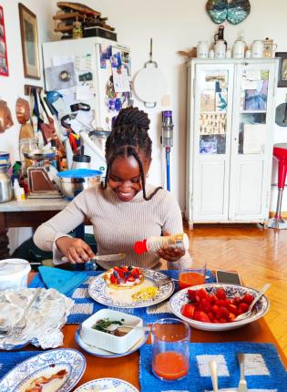 A student enjoying brunch in her homestay, eating pancakes with fruit on blue patterned plates.