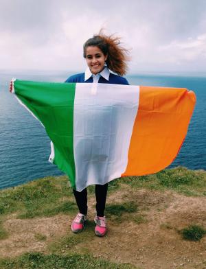 dublin student holding an Irish flag at the Cliffs of Moher