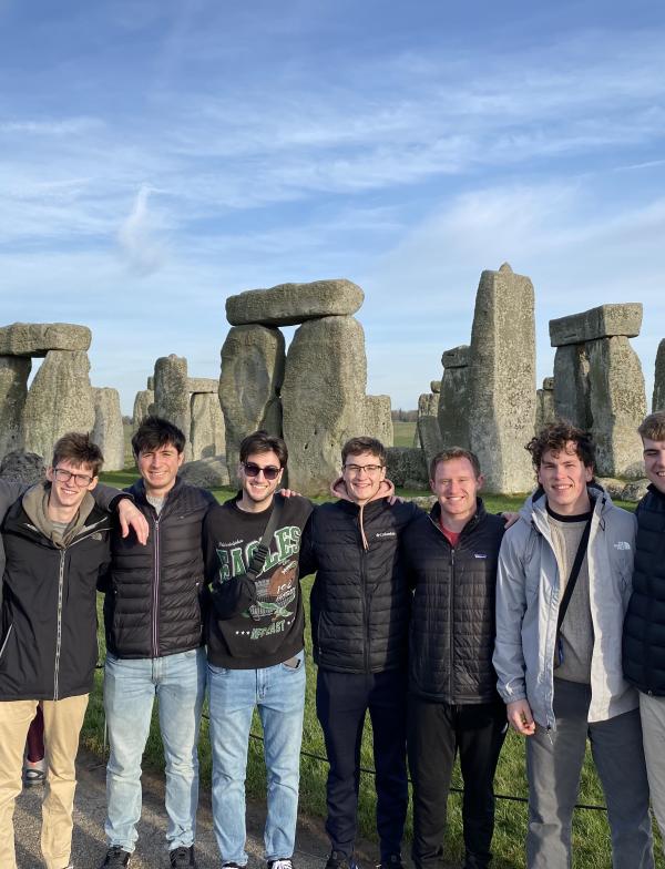 group of students standing in front of the famous stonehenge, stacked rocks