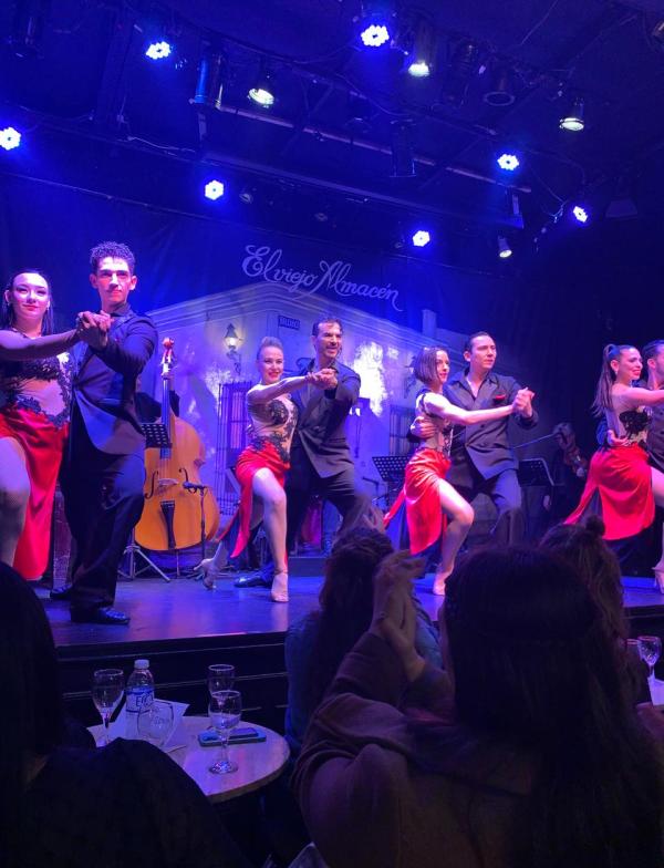 students in the audience of a tango show, which is happening behind them