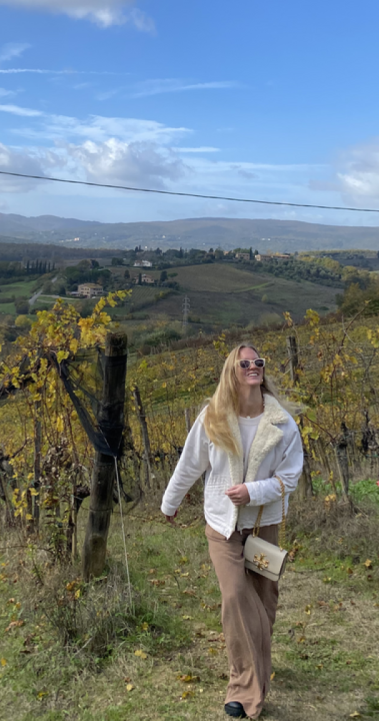 A girl walking in the wine fields of Siena.