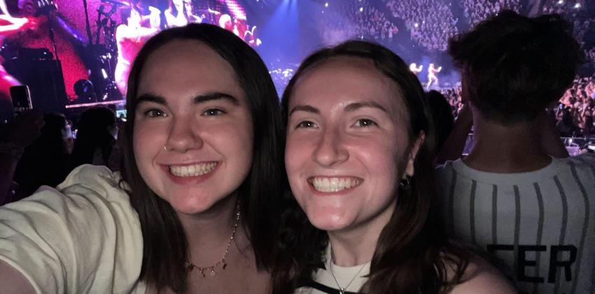 the photo is taken at concert; there are two smiling girls who took the selfie