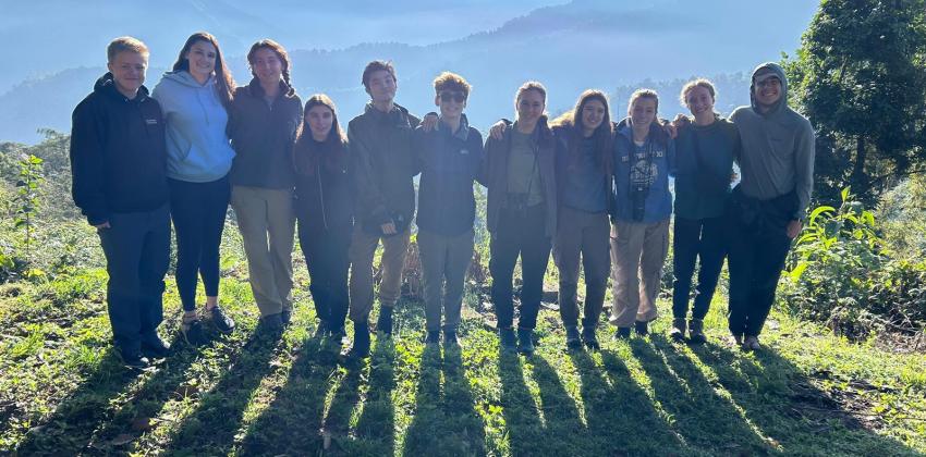 Group of people standing together with a background of mountains. 