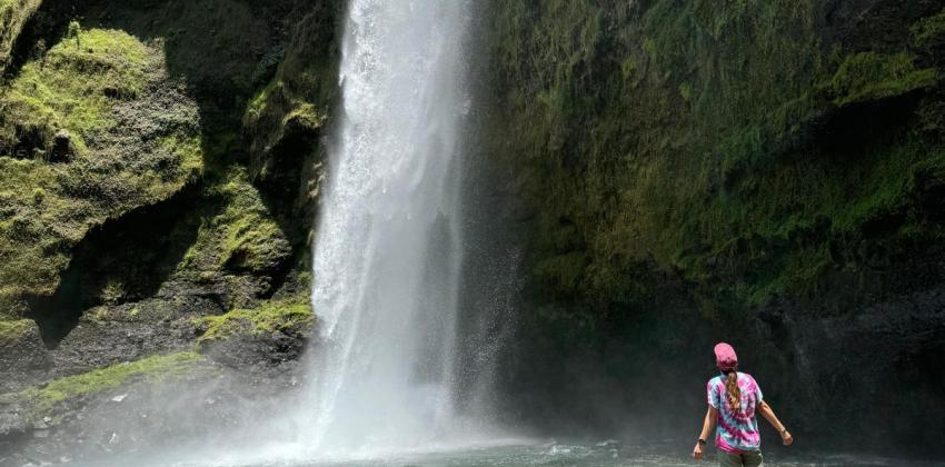 Picture of female standing in front of large waterfall.